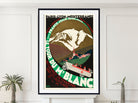 A framed vintage travel poster for 'Le Tour du Mène Blanc' is displayed on a white wall above a mantel, flanked by small potted plants. The poster features a retro design with a snow-covered mountain, a vintage car, and bold green and red typography.