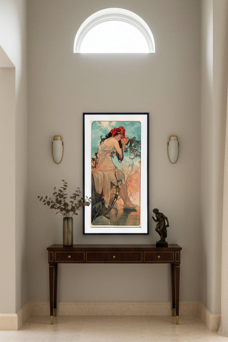 A framed vintage Art Nouveau style print featuring a seated woman in flowing pale drapery, with a red flower crown, against a sky-like background in blue, peach, and orange tones.