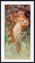 A framed Art Nouveau style print featuring a woman in a flowing white dress among flowering branches and foliage, with a black frame and white mat around the artwork.