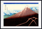 A framed Japanese-style art print depicting Mount Fuji, with a dark foreground, blue sky, white clouds, and a snow-capped mountain, shown against a white mat and black frame.