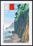A framed Japanese ukiyo-e woodblock print depicting a coastal landscape with steep dark cliffs, green vegetation, blue water, and a small figure near the shore. The print includes a red title box with black calligraphy and is shown with a white mat and black frame.
