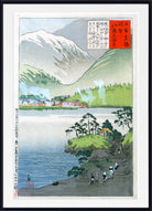 A framed Japanese-style landscape print showing a lake, green hills, a snow-capped mountain, small houses, and a red text panel, presented against a white mat and black frame.