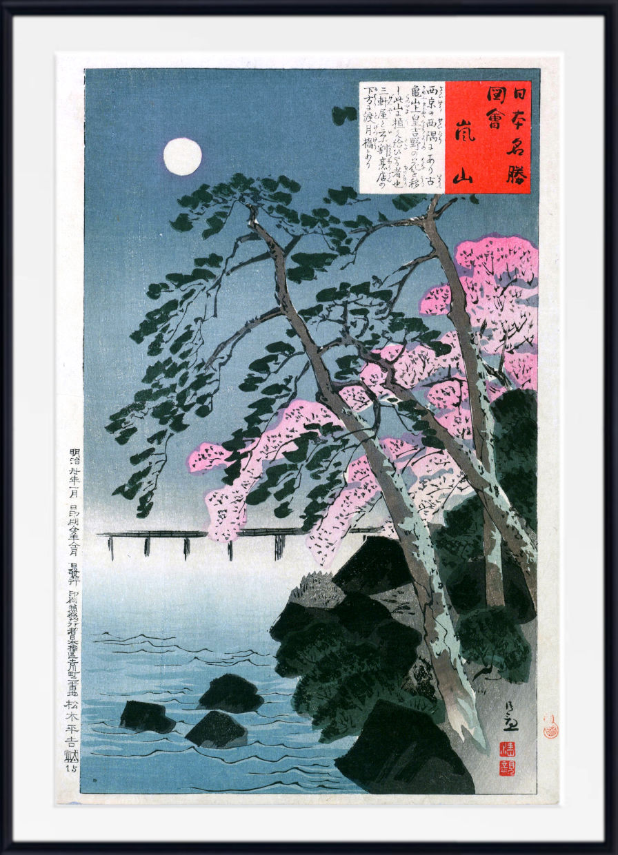 A framed Japanese ukiyo-e woodblock print depicting a moonlit scene with pink cherry blossoms, dark rocks, a bridge over water, and a blue sky. The print includes a white mat and a black frame.