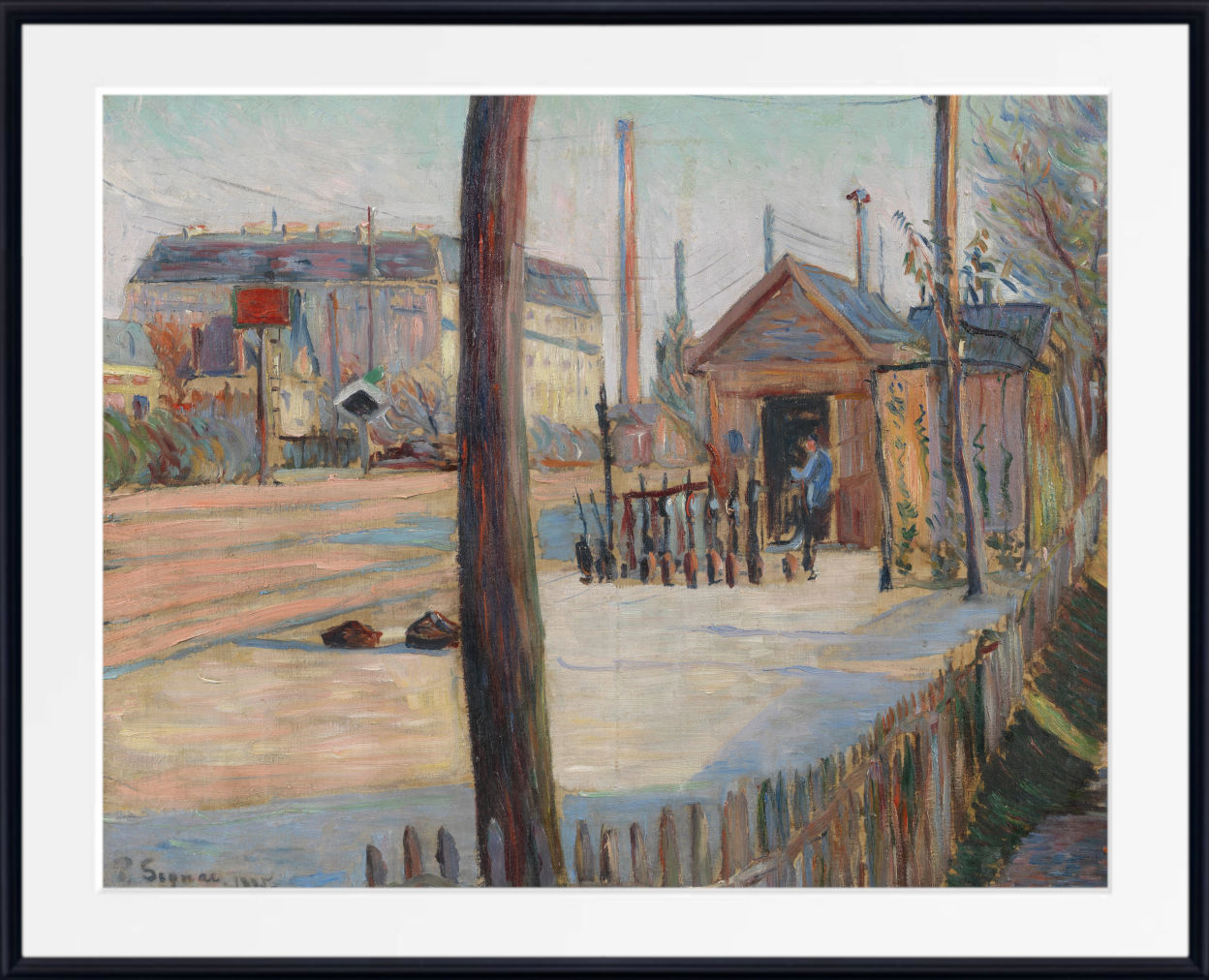 A framed impressionist painting depicting an outdoor industrial street scene with buildings, a small hut, fence, and trees, shown with a white mat and black frame.