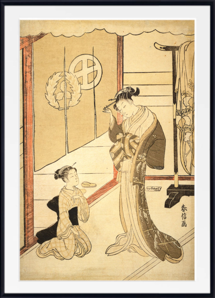 A framed Japanese ukiyo-e woodblock print showing two women in an interior scene, with one kneeling and one standing, on aged beige paper with a white mat and black frame.