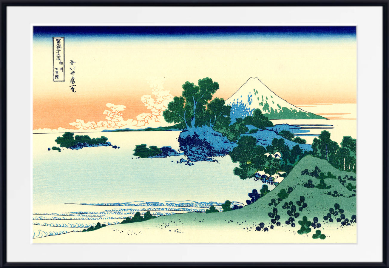 A framed Japanese-style landscape print showing a snow-capped mountain, water, trees, and a pale sky, with a white mat and black frame.