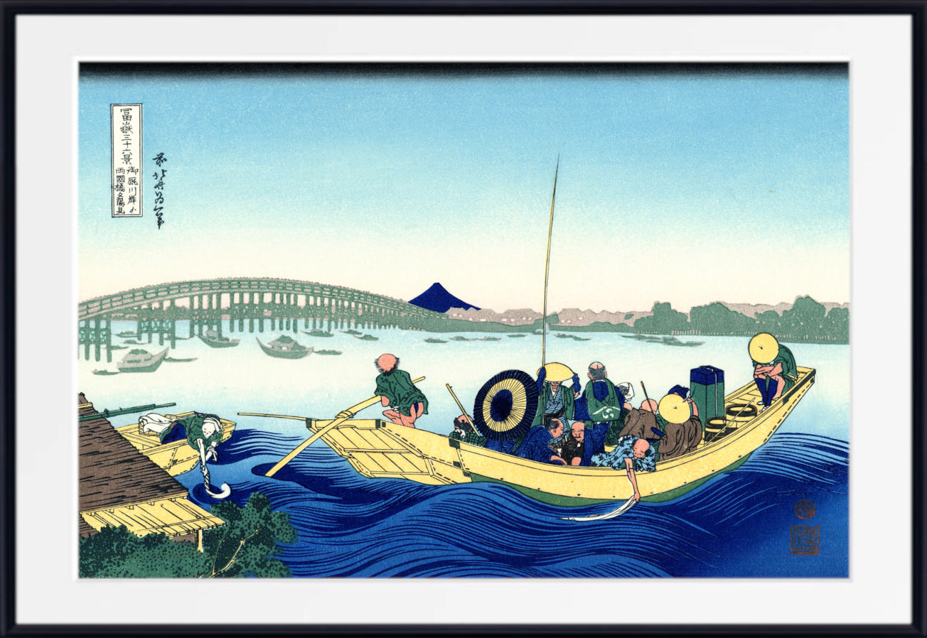 A framed Japanese woodblock-style print showing a boat with several figures on blue water, with a bridge, distant mountain, and pale sky. The print is centered within a white mat and a black frame.