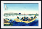 A framed Japanese woodblock-style print showing a boat with several figures on blue water, with a bridge, distant mountain, and pale sky. The print is centered within a white mat and a black frame.