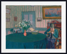 A framed art print of an impressionist painting depicting a woman sewing in a room with striped wallpaper, a blue table, and a vase of white flowers.