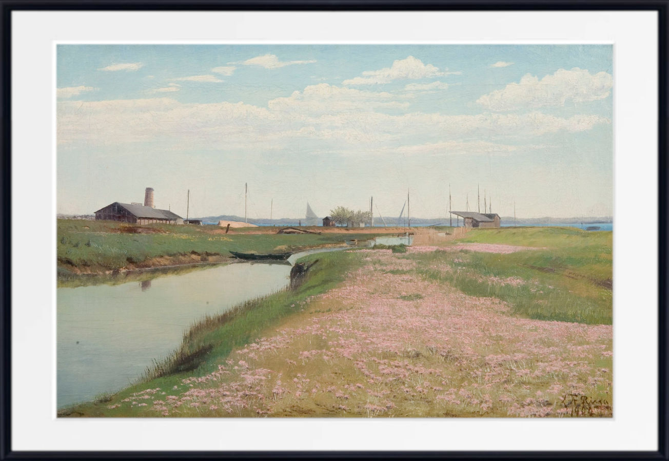 A framed landscape painting depicting a grassy field with pink flowers, a canal, distant buildings, and a cloudy sky, shown with a wide white mat and black frame.