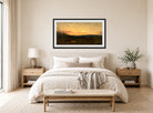 Amaldus Nielsen Print, Solnedgang ved seteren (1866) displayed above a bed
