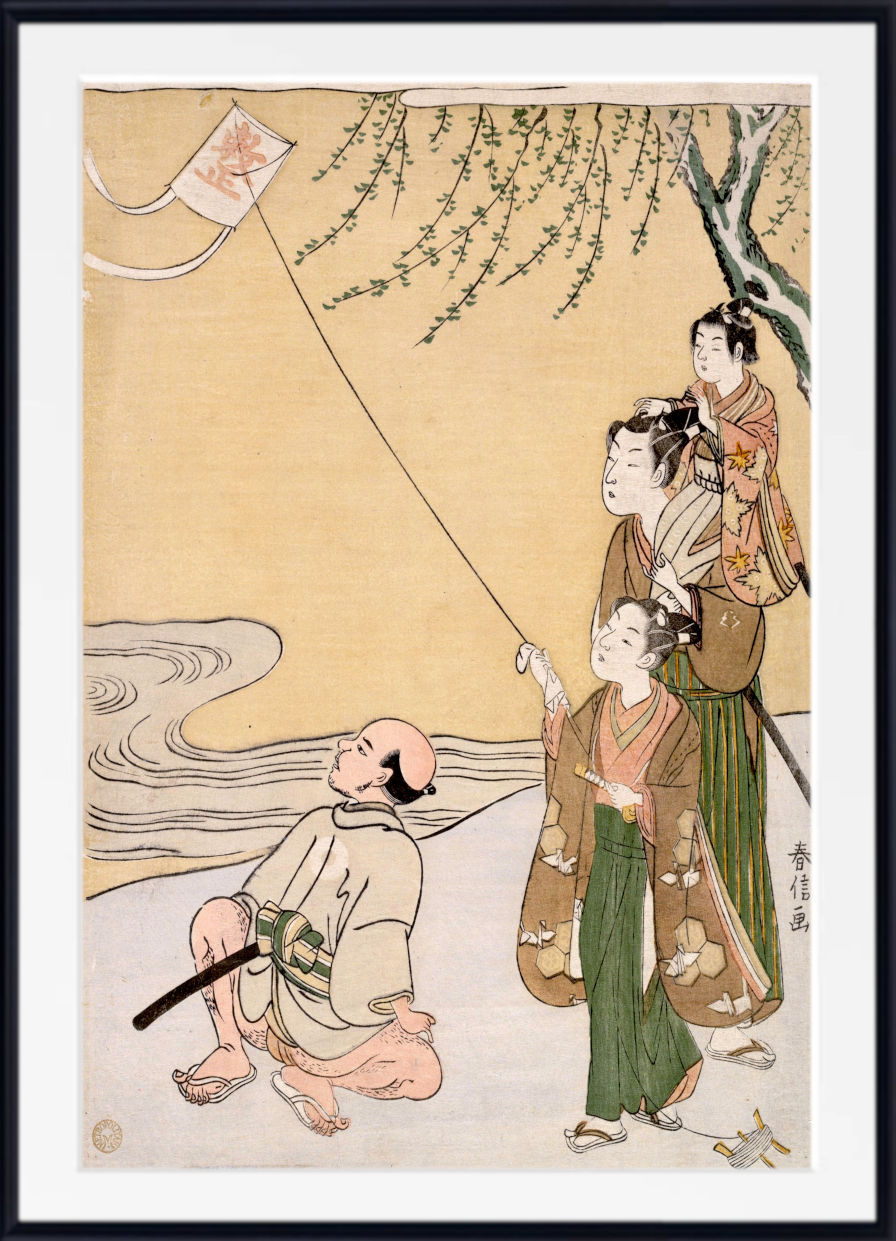 A framed Japanese ukiyo-e woodblock print showing three women in traditional robes flying a kite near a tree by a river, with a black frame and white mat border.