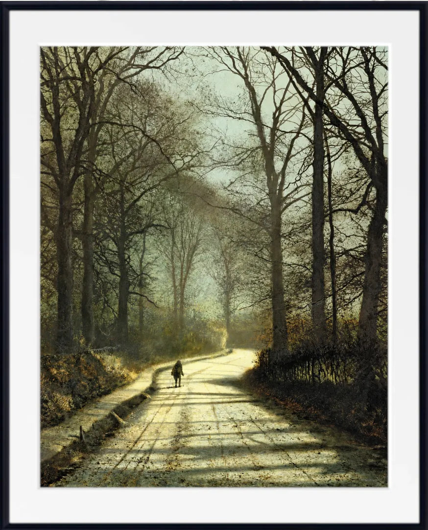 A framed art print depicting a misty, sunlit path winding through a forest of tall, bare trees, with a small figure walking in the distance. The print is matted with a wide white border and enclosed in a thin black frame. John Atkinson Grimshaw Print: Moonlight Walk
